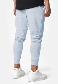 Lichtblauwe katoenen joggers met ribbels aan de manchetten, zijzakken en een ontspannen pasvorm, gecombineerd met witte sneakers.