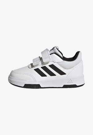 White athletic shoe with black accents. Features Velcro straps, synthetic material, and a textured sole. Three black stripes on the side.