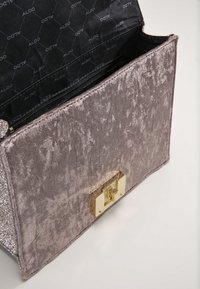 Borsa grigia con texture e finitura morbida simile al velluto. Presenta una chiusura in metallo dorato e un interno nero con branding impresso.