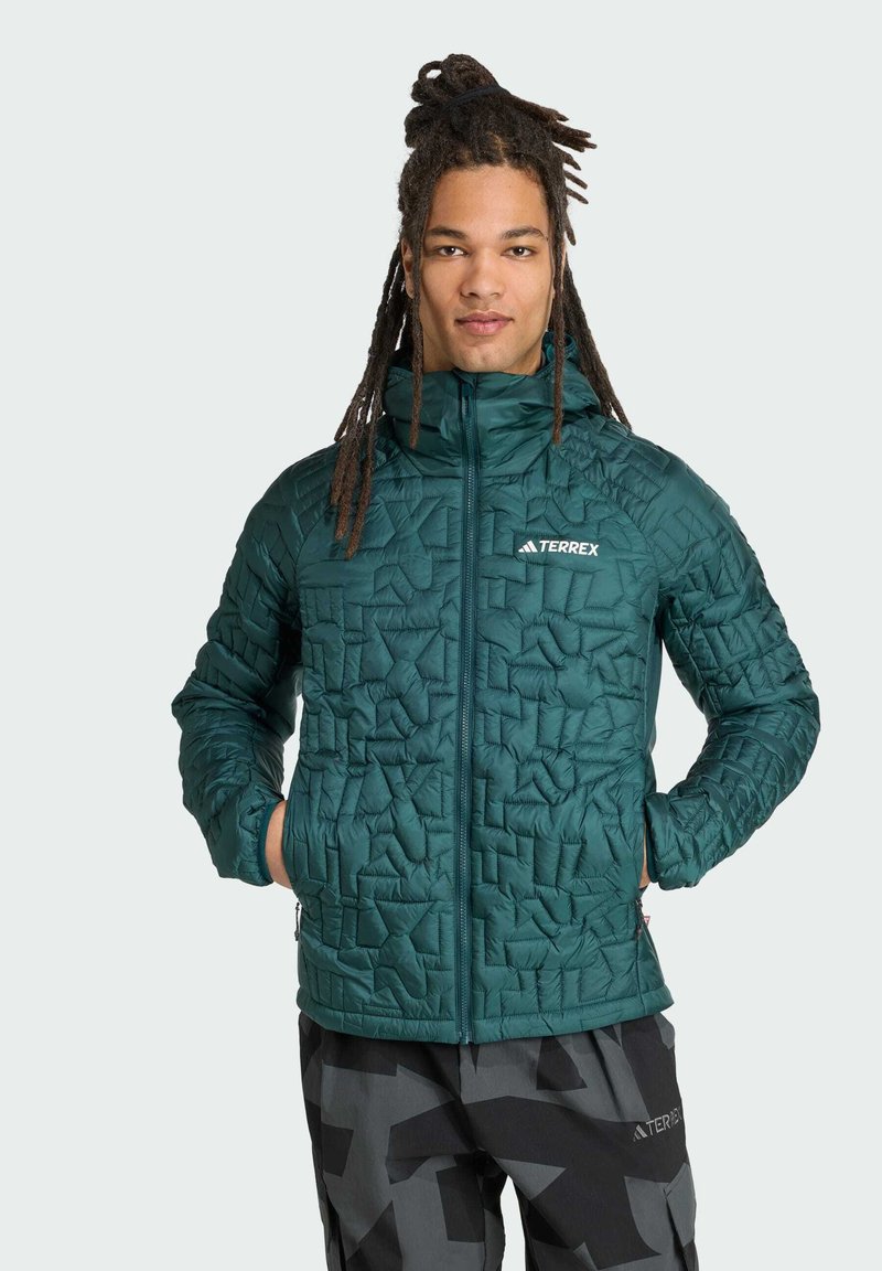 Groene gewatteerde jas met een gestructureerd, geometrisch patroon, rits aan de voorkant en fleece-gevoerde zakken. Voorzien van een capuchon en elastische manchetten.