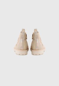 Beige ankle boots made of iridescent material with a textured finish, featuring a solid sole and two pull tabs on the back.