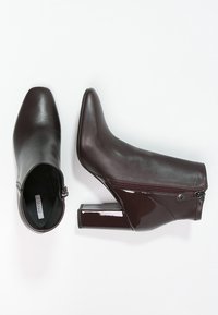 Burgundowe botki za kostkę z gładkiej skóry, z zamkiem błyskawicznym po boku i błyszczącej, kwadratowej obcasie, z wąskim noskiem.