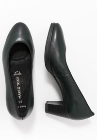 Pair of dark green leather women's block heel shoes, one showing top view with brand name, the other showing side profile on white background.