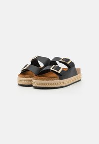 Black platform sandals with dual adjustable buckles, jute-wrapped midsole, textured footbed, and rubber outsole. Gold-colored bead accents.