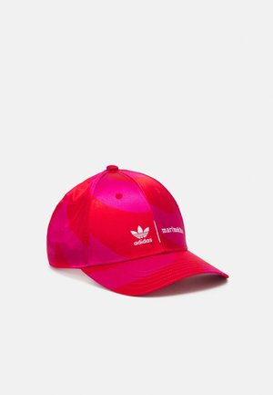 Casquette de baseball rouge et rose à motifs avec le logo Adidas et le texte Marimekko sur le panneau avant, sur un fond blanc uni.