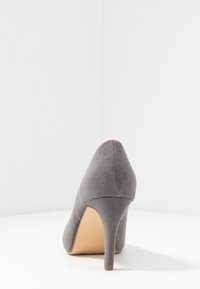 Šedé nubukové lodičky na vysokém podpatku s špičatou špičkou a štíhlým podpatkem; mají hladkou texturu a neutrální barvu, vhodné pro všestranné styling.