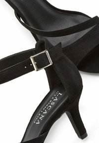 Schwarze Wildleder High-Heelsandalen mit dünnen Riemen und einer quadratischen Schnalle. Mit einem glatten Innenfutter und einem konischen Absatz.