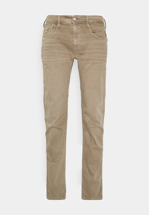 Beige slim-fit jeans made of soft cotton fabric, featuring five pockets, a zipper fly, and subtle stitching details along the seams.