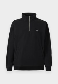 Czarny polarowy sweter z wysokim kołnierzem, srebrnym zamkiem z przodu, dwoma bocznymi kieszeniami oraz białym haftowanym logo "OBEY" na piersi.