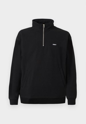 Black fleece sweatshirt with a high collar, silver front zipper, two side pockets, and white embroidered "OBEY" logo on the chest.