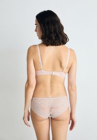 Spitzen-BH und passendes Höschen-Set in sanftem Rosa, mit zarten Blumenmustern, verstellbaren Trägern und einem Haken- und Ösenverschluss auf der Rückseite.