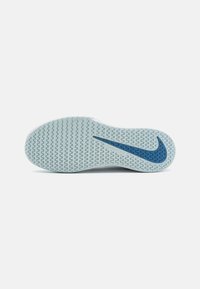 Nike cipőtalp, világoskék gumiból készült, texturált zigzag mintázattal, az oldalán egy sötétkék logóval és sima, ívelt formával.