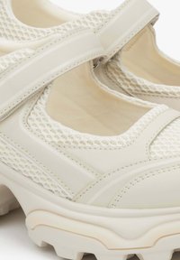 Lichtbeige sport schoenen met een bovenwerk van mesh, gevoerde binnenkant en rubberen zool. Voorzien van een verstelbare band en getextureerde details op het oppervlak.