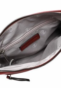 Interior de un bolso de mano de cuero rojo con un forro gris suave, que cuenta con un bolsillo con cremallera y una etiqueta de la marca. Cierre de cremallera a lo largo del borde superior.