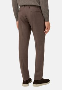 Hnědé kalhoty na míru z texturovaného materiálu, s dvěma zadními kapsami a úzkým střihem, doplněné tmavohnědými mokasíny.