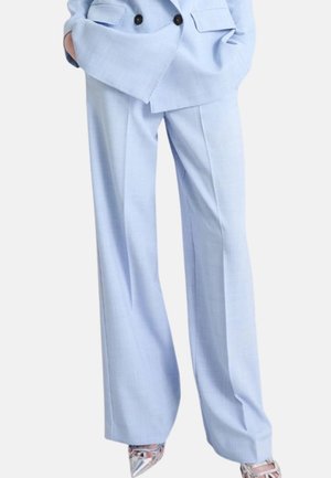 Pantaloni a gamba larga azzurri abbinati a un blazer doppiopetto coordinato e décolleté argento con punta.