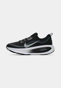 Zwarte en grijze Nike hardloopschoen met een witte ZoomX zool, Gore-Tex merknaam en een treklabel op de hiel, gezien vanaf de buitenzijde.