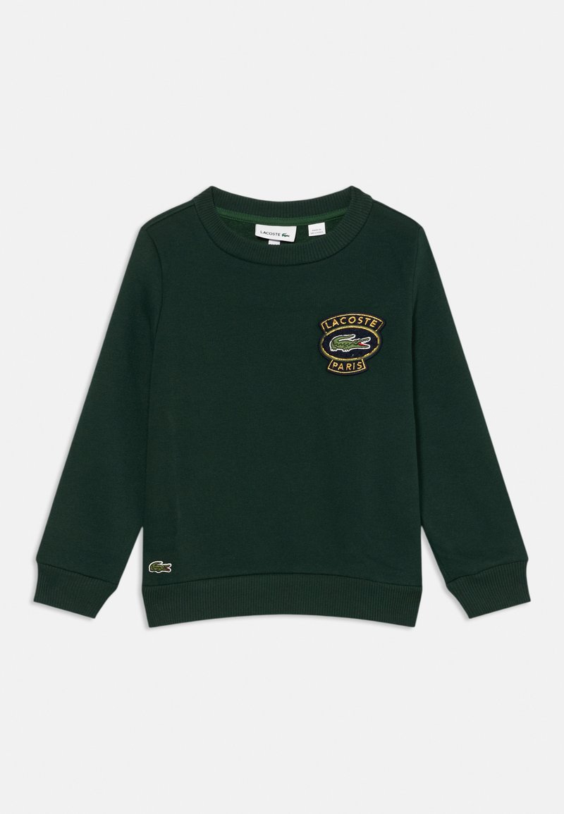 Sudadera de algodón verde con cuello redondo y puños acanalados. Presenta un parche con el logo de Lacoste en el pecho y un pequeño logo en el dobladillo.