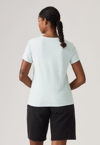 Ανοιχτό μπλε βαμβακερό μπλουζάκι με κοντά μανίκια και στρογγυλή λαιμόκοψη, συνδυασμένο με μαύρα τζιν σορτς. Απλός σχεδιασμός χωρίς εμφανή σχέδια.