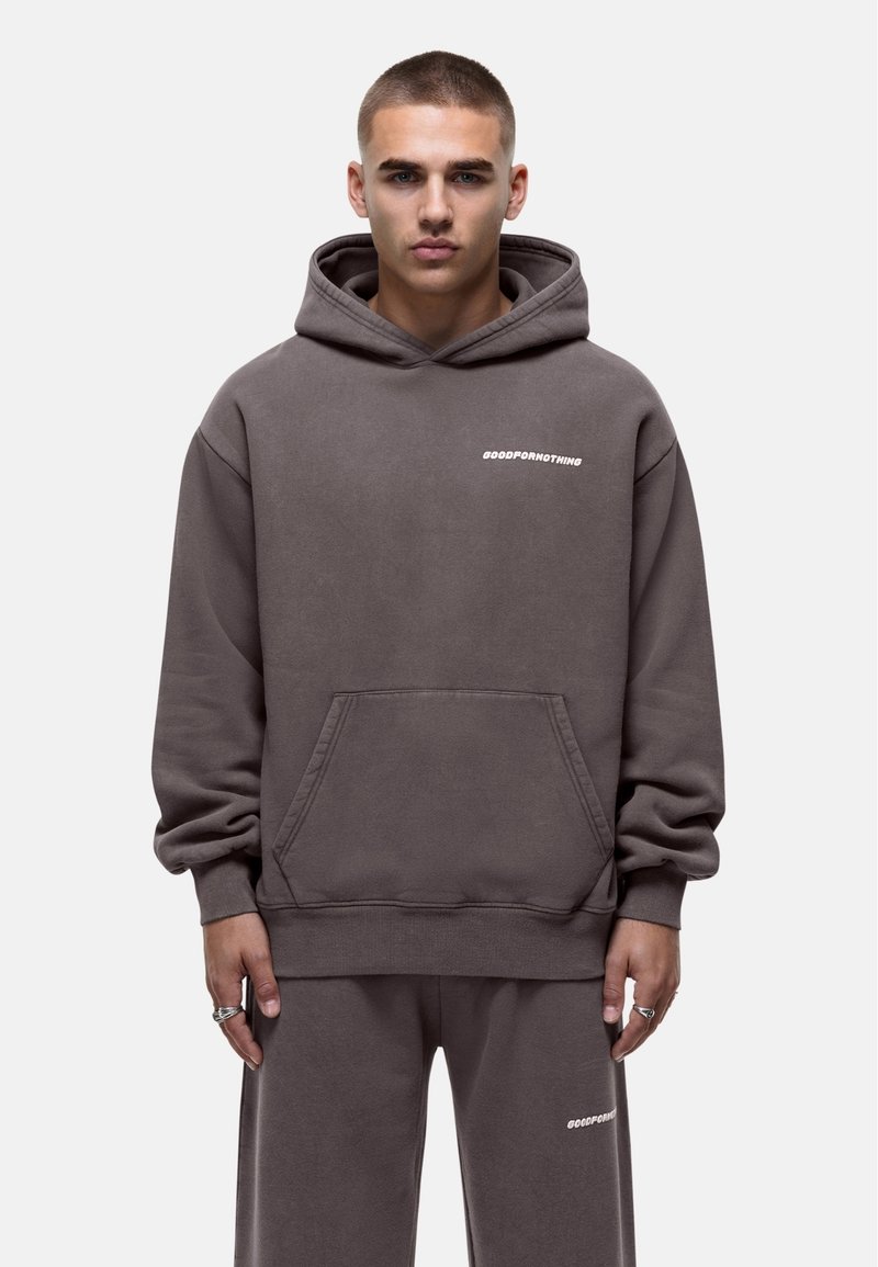 Grijze hoodie met witte tekstlogo, buidelzak en geribbelde manchetten. Soepele stof, relaxed fit, gecombineerd met bijpassende broek.