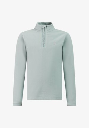 Jongen staat en draagt een lichtblauwe fleece met een kwart ritssluiting, zwarte broek en zwarte schoenen tegen een effen lichte achtergrond.