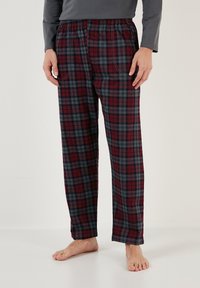 Pantalones de pijama a cuadros rojos y grises con cintura elástica, dos bolsillos laterales y diseño de pierna recta. Tejido de mezcla de algodón.