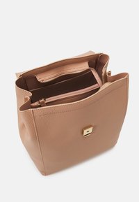Sac fourre-tout en cuir rose clair avec une surface texturée, doté d'un fermoir carré en or et de plusieurs poches intérieures, y compris une section zippée.