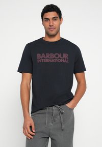 Mustast puuvillast t-särk mahukate tumepunaste "BARBOUR INTERNATIONAL" kirjaga, ümara kaelusega, lühikeste varrukatega, hallide nöörkinnitusega pükstega.