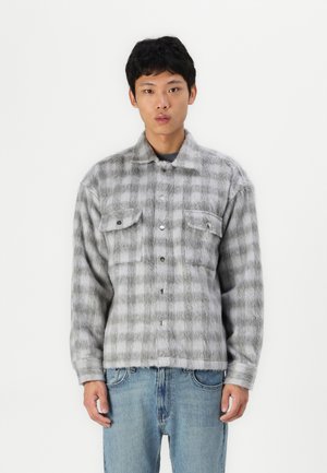 Grijs geruit overhemd van fuzzy materiaal, met twee borstzakken en een rechte zoom, gedragen over denim spijkerbroeken.