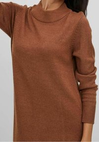 Abito maglione marrone a maglia con colletto alto a coste, maniche lunghe e texture morbida. Presenta dettagli sottili sulle spalle e sui polsini.