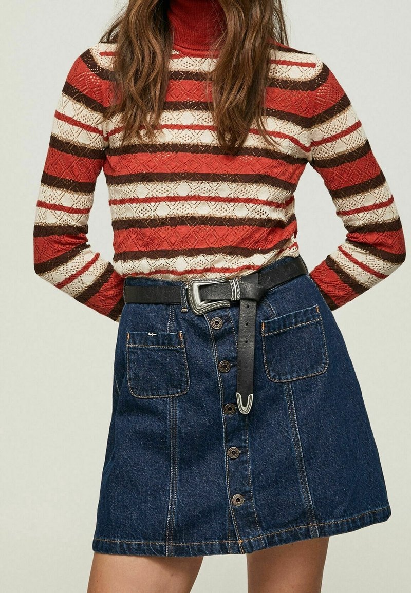 Röd och krämfärgad randig stickad tröja med hög hals, kombinerad med en mörk denim A-linjekjol med framknappar och ett svart bälte.