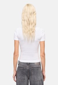 Witte aansluitende t-shirt met korte mouwen, gecombineerd met hooggeplaagde, vervaagde grijze jeans met twee achterzakken.
