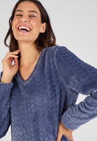 Maglione felpato blu con scollatura a V, motivo testurizzato, maniche lunghe e vestibilità comoda. Materiale morbido e soffice aggiunge comfort e calore.