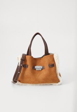 Brown suede handbag with dark leather handles and strap, silver clasp, and cream shearling trim on white background.