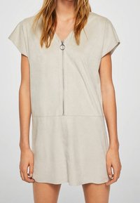 Svetle šedé krátké šaty z jemné tkaniny, s výstřihem do V a krátkými rukávy. Centrální zip s kruhovým táhlem podtrhuje design.