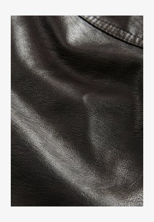 Czarna sztuczna skóra o teksturowanej powierzchni, z delikatnymi zmarszczkami i gładkim połyskiem, świadcząca o elastyczności i miękkości.