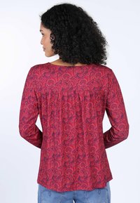 Rotes, floral bedrucktes Langarmoberteil mit einer gerafften Rückendetail und einer glatten Stoffoberfläche, runder Halsausschnitt und geschwungener Saum.