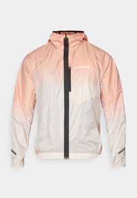 Lett rosa gradient jakke med svart frontglidelås, justerbar hette og brystlomme. Har teksturert materiale og logoaccent.