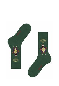 Grüne Baumwollsocken im "Santa Wrapper"-Design mit roten und goldenen Akzenten, die eine geschenkverpackte Figur mit einem festlichen Muster darstellen.