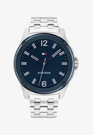 Montre en acier inoxydable argenté avec un cadran bleu marine, des index blancs et un accent rouge. Elle dispose d'un bracelet à maillons et d'un boîtier rond.