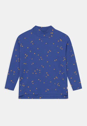 Chemise à col roulé manches longues bleue avec des motifs orange de soleil, lune et étoiles, dotée d'un ourlet arrière légèrement plus long et d'une petite étiquette latérale.
