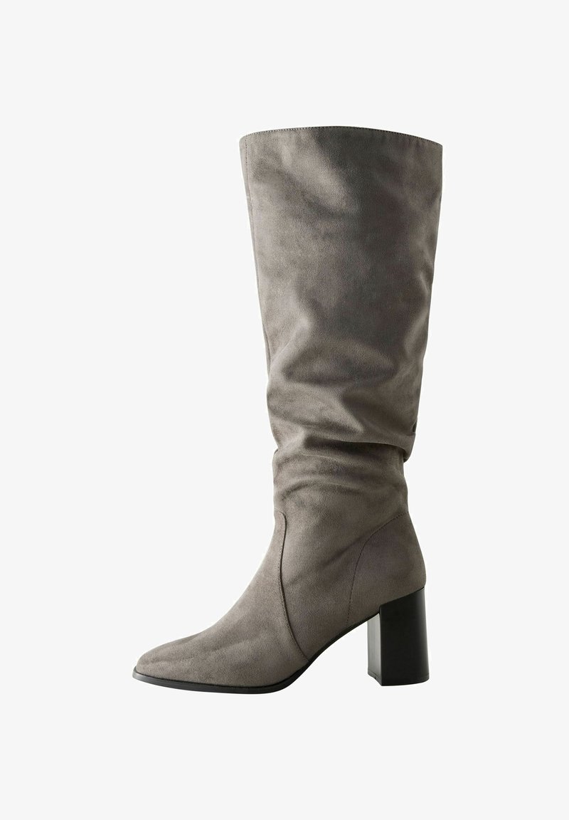 Botte grise en suède, haute jusqu'au genou, au design flou, avec un bout pointu et un talon chunky noir. Texture lisse avec des détails de couture visibles.