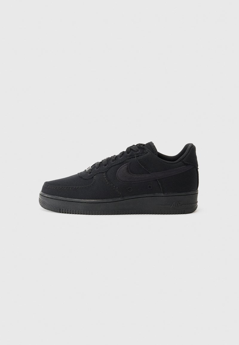 Svart sneaker med overdels i lerret og syntetisk materiale, med rund tå, flate snørebånd, polstret krage og en strukturert gummisåle.