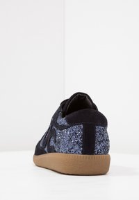 Baskets bleu marine foncé avec une finition pailletée sur les côtés, matériau en daim, bout arrondi et semelle en gomme texturée.