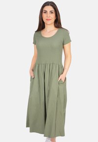 Olivegrünes Kurzarmkleid mit einer enganliegenden gerippten Oberseite und einem fließenden, gestuften Rock, der Seitentaschen und einen weichen, strukturierten Stoff aufweist.