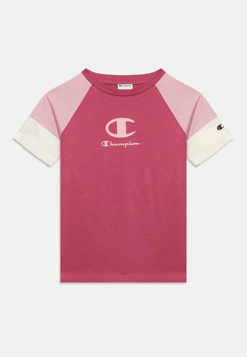 T-shirt raglan à manches courtes avec corps rose, épaules rose clair, poignets blancs aux manches et logo Champion sur la poitrine et la manche.