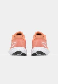 Chaussures de course avec une tige en maille rose légère, un intermédiaire blanc et une semelle extérieure en caoutchouc noir. Logo notable et détails texturés au niveau du talon.