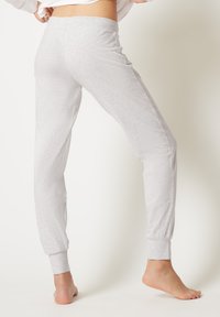 Lichtgrijze joggingsbroeken gemaakt van zachte stof, met elastische boorden en een ontspannen pasvorm. Gladde textuur met minimale ontwerpdetails.