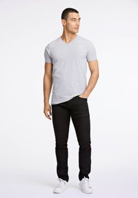 Szara koszulka V-neck, krótki rękaw, w połączeniu z czarnymi dżinsami slim fit i białymi trampkami. Gładki materiał, casualowy styl, minimalne detale.