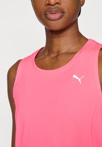 Φλούο ροζ αμάνικη μπλούζα από υφασμάτινη υφή, με λευκό λογότυπο Puma στην αριστερή πλευρά του στήθους. Απλός και λειτουργικός σχεδιασμός.